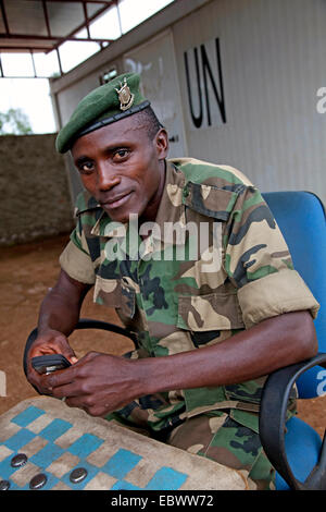 Soldato responsabile per la sicurezza di un campo buero dell ONU è la riproduzione di bozze con un compagno tra i contenitori con il logo dell'organizzazione, Burundi, Makamba, Makamba Foto Stock