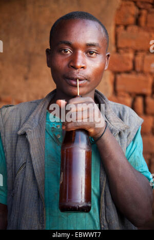 Giovane uomo dringing birra tradizionale con una cannuccia, Burundi, Cankuzo, vicino al Parco Nazionale de la Ruvubu, Cankuzo Foto Stock