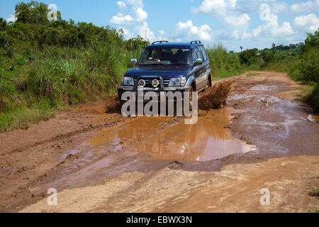 Cross-country a veicolo in marcia attraverso un pozzo del fango su un suolo di strada attraverso la boccola del paesaggio, Burundi, Cankuzo, Nazionale Parc de la Ruvubu, Cankuzo Foto Stock