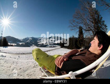 L'uomo rilassante nella neve su una sedia di canvas, Austria, Tirolo, Hopfgarten Foto Stock
