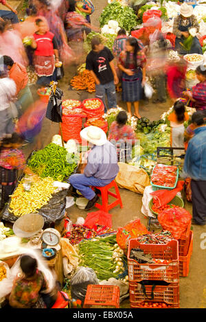 I fornitori locali in insolito angolo birdseye dal di sopra con movimento sfocata in colorati vestiti stampati nella frutta shopping center sul giorno di mercato, Guatemala, Chichicastenango Foto Stock