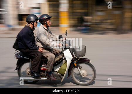 Due uomini anziani cavalcare attraverso la città su uno scooter a motore, Vietnam, Hanoi Foto Stock