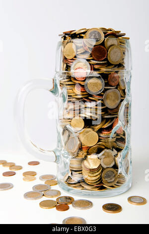 Molte monete in euro nella tazza di vetro Foto Stock