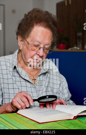 Vecchia donna con gli occhiali per leggere un libro Foto Stock