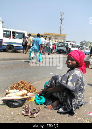 Scena di strada nella città capitale; giovane donna sulla terra la vendita di manioca e arachidi per passeggeri presso la stazione centrale degli autobus vicino al mercato, Burundi Bujumbura marie, Bujumbura Foto Stock