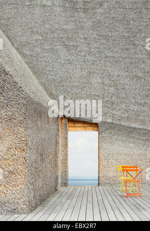 Moderno edificio con tetto di paglia e terrazza con vista sul lago Foto Stock