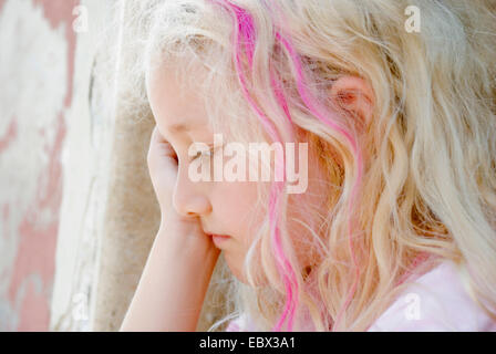 Ragazza triste accovacciato a una parete Foto Stock