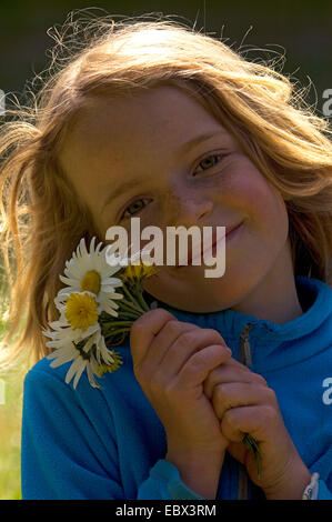 Ritratto di un sorridente bimba di 8 anni, con un mazzetto di margherite in mano, Francia Foto Stock