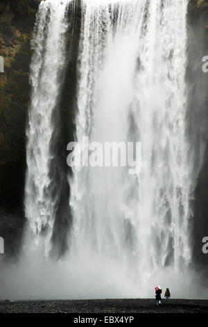 Piccoli visitatori alla cascata Skogafoss/Skogarfoss che è colata una monumentale parete di roccia, Islanda, Sued Isola Foto Stock