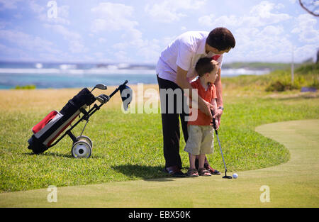 Padre ad insegnare la sua sun giocare a golf su un campo da golf Foto Stock