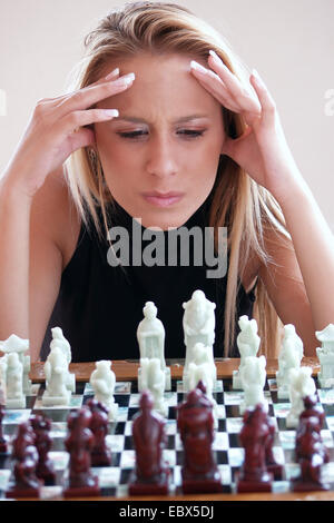 Giovane donna bionda seduti davanti ad una scacchiera di pensare Foto Stock
