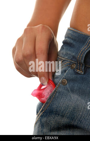 La donna la mano tirando un preservativo fuori da una tasca dei pantaloni Foto Stock