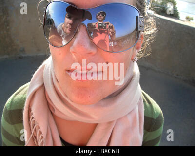 Donna che indossa gli occhiali da sole, fotografo è riflessa negli occhiali da sole Foto Stock