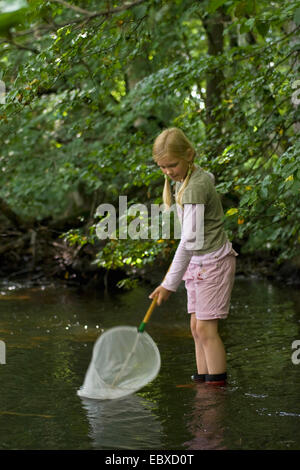 Ragazza con stivali di gomma e un calo netto, in piedi in un torrente Foto Stock