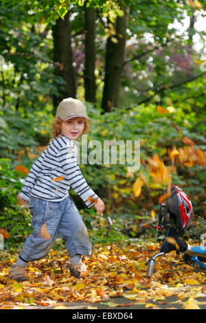 Little Boy gettando autmn fogliame di distanza Foto Stock