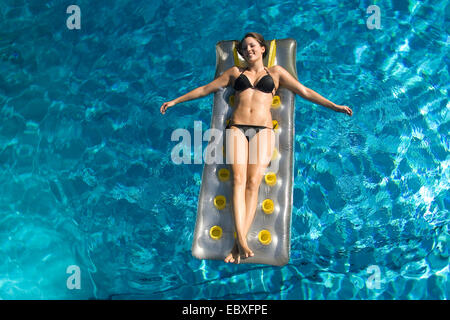 Giovane donna sul materasso ad aria in una piscina, Austria Foto Stock