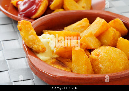 Ingrandimento di una piastra con tipico spagnolo patatas bianche, patate fritte con una salsa calda Foto Stock