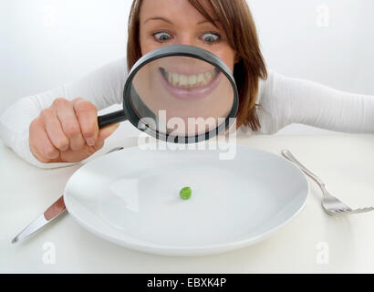 Donna con lente di ingrandimento visualizzato il segnale di PEA in corrispondenza della piastra Foto Stock