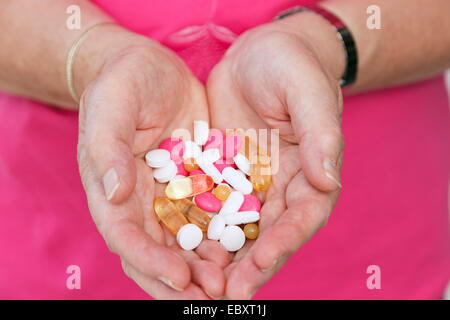 Donna anziana tenendo una selezione di prescrizione e integrare le pillole nel palmo delle due mani. Inghilterra, Regno Unito, Gran Bretagna Foto Stock