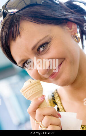 Giovane donna in abiti estivi a mangiare il gelato Foto Stock