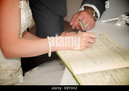 Sposa e lo sposo di firmare il registro di matrimonio Foto Stock