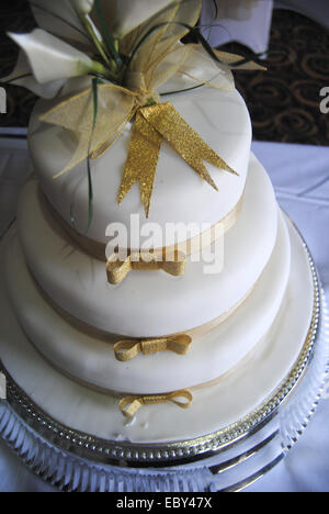 Bianco torta di nozze con il ricevimento di nozze in background. Foto Stock