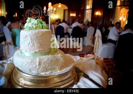 Bianco torta di nozze con il ricevimento di nozze in background. Foto Stock