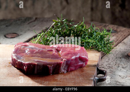 Una bistecca su un tagliere di legno pronto per il barbecue Foto Stock