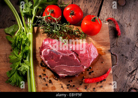 Una bistecca su un tagliere di legno pronto per il barbecue Foto Stock