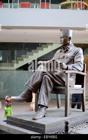 Blitar, Indonesia. Agosto 13, 2013 -- Un bambino è sotto la statua di Sukarno presso la tomba del primo presidente indonesiano Sukar Foto Stock