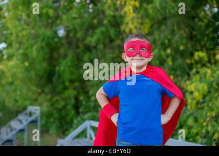 Ragazzo vestito in capo e la maschera in piedi con le mani sui fianchi e sorridente Foto Stock