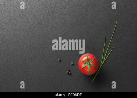 Rosso Pomodoro con cipolla verde su nero Foto Stock