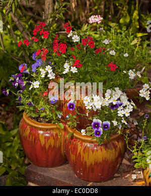 Display a colori della fioritura annuari, viola, Red & White pansies & nemesias fuoriuscita dagli elementi decorativi tiered pentole di fragola Foto Stock