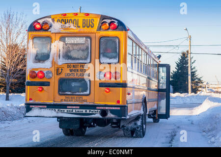 Un tipico giallo scuola bus si fermava a prelevare i passeggeri su un estremamente freddo giorno d'inverno. Foto Stock