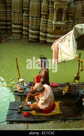 Due uomini in preghiera presso il fiume Gange a varanasi in India Foto Stock