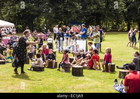 Storyteller con bambini seduti intorno sull'erba; proseguendo un antico bardo la tradizione. In Kenwood House motivi, Hampstead Foto Stock