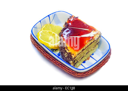 In un bel vaso di ceramica è il dessert: una deliziosa torta e due fette di limone. Presentato su uno sfondo bianco. Foto Stock