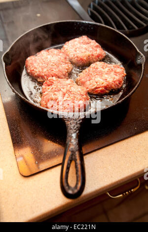 Salcicce calde le polpette una cottura in ghisa nera padella su un fornello. Foto Stock