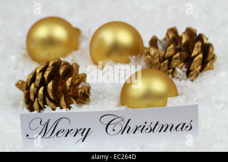 Merry Christmas card con golden baubles e pigne sulla superficie nevosa Foto Stock