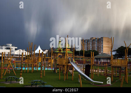 Jungle Jim giochi, stile Tolkien legname zona gioco parte del rinnovato Kings Gardens, nel parco, Southport, Merseyside UKVirga con fall-striature in caduta da nimbostratus inverno meteo formazioni di nubi. Virga è una striatura osservabili o albero di precipitazione da una nuvola ma di evaporazione o sublimazione prima di raggiungere il suolo. Dopo i temporali e la comparsa di un fronte freddo nelle prime ore del mattino, il resort costiero permane alta venti, deboli nevicate, pioggia e grandine, con sole intermittente. Foto Stock