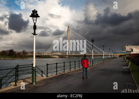 Uomo che cammina Alonside Marine Lake,. Lungomare 'Kings Gardens', Southport, Merseyside, Regno Unito. Dicembre 2014. Regno Unito Meteo. Dopo temporali nelle prime ore, la località costiera resiste a venti alti, pioggia e grandine, con sole intermittente. Foto Stock