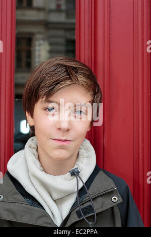 Ritratto di un bel ragazzo adolescente di fronte ad una porta rossa Foto Stock