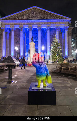 Statua colorata di Paddington Bear promuovere il film al di fuori del illuminato blu Royal Exchange, City of London, in aiuto del NSPCC, di notte Foto Stock