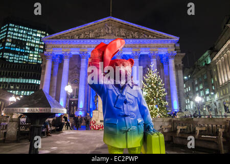 Statua colorata di Paddington Bear promuovere il film al di fuori del illuminato blu Royal Exchange, City of London, in aiuto del NSPCC, di notte Foto Stock