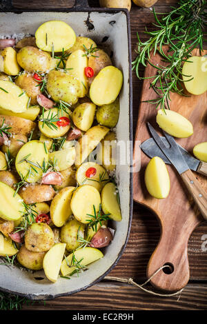 La preparazione di patate al forno con erbe e aglio Foto Stock
