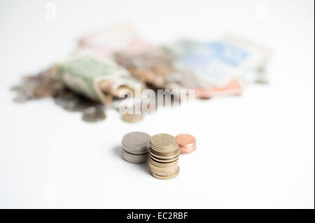 Tre pile di monete, oro, argento e bronzo, con la montagna di denaro delle monete e delle banconote in euro al di fuori della messa a fuoco in background Foto Stock