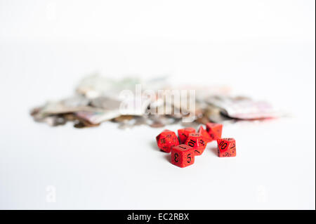 Dadi rossi con fuori fuoco denaro in background Foto Stock
