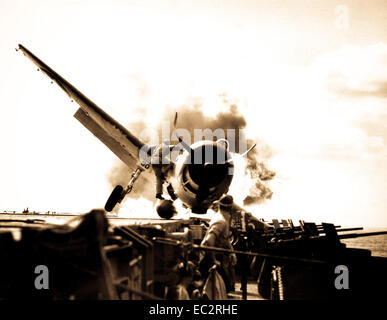 Crash di f6f sul ponte di volo della USS Enterprise mentre lungo il tragitto per attaccare makin island. lt. Walter chewning, catapult officer, clambering fino al lato del piano per assistere pilota, ens. Byron Johnson, dall'ardente cockpit. novembre 1943. (Marina) Foto Stock