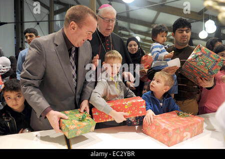 FILE - un file immagine datata 16 dicembre 2013 mostra il Ministro degli Interni della Bassa Sassonia Boris Pistorius (SPD, L) e il vescovo della Diocesi di Hildesheim Treller Norbert (2-L) che mano regali durante la festa di Natale a Friedland camp per i richiedenti asilo e etnici emigrante tedesco. Quest anno la festa di Natale presso il camp avrà luogo il 09 dicembre 2014. Foto: Swen Pfoertner/dpa Foto Stock