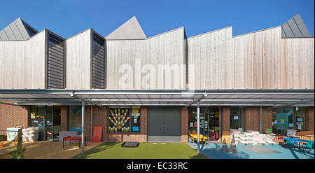 Hollymount School di Londra, Regno Unito. Architetto: Haverstock Associates LLP, 2013. Elevazione panoramica di edificio con gioco Foto Stock